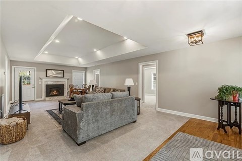 A spacious living room with a grey couch and a fireplace.