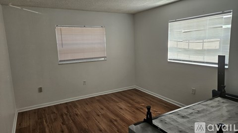 A room with wooden flooring and a window with blinds.