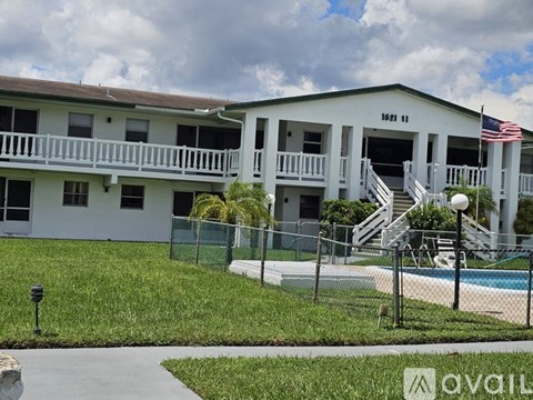 A white building with a pool in front and an American flag hanging on the wall.