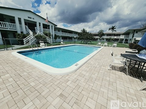 A large swimming pool surrounded by a tiled floor and a building with the number 1111 on it.