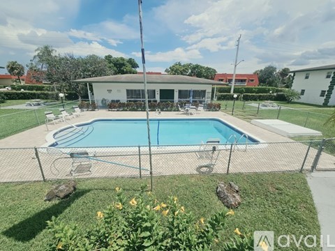 A pool surrounded by a fence with a house in the background.