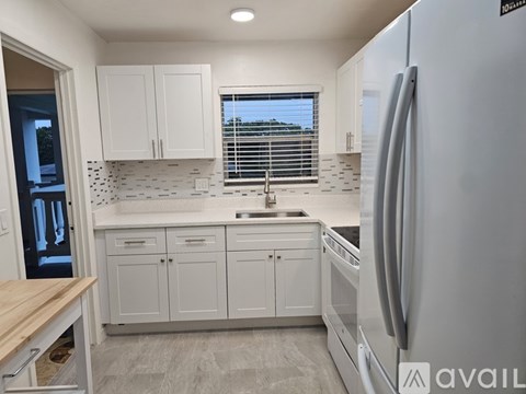 A kitchen with white cabinets and a refrigerator.