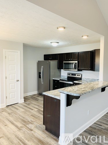 A kitchen with a refrigerator, microwave, and oven.