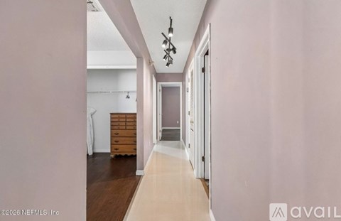 A hallway with a chandelier and a door on the right.
