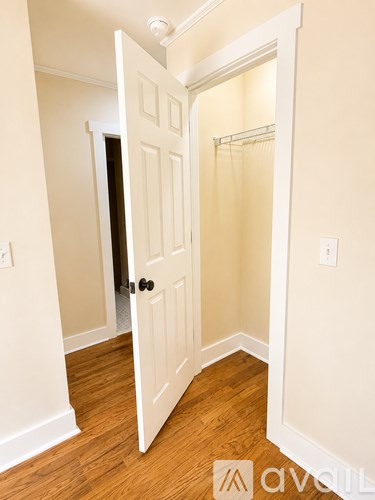 A white door is open to a small room with wood flooring.