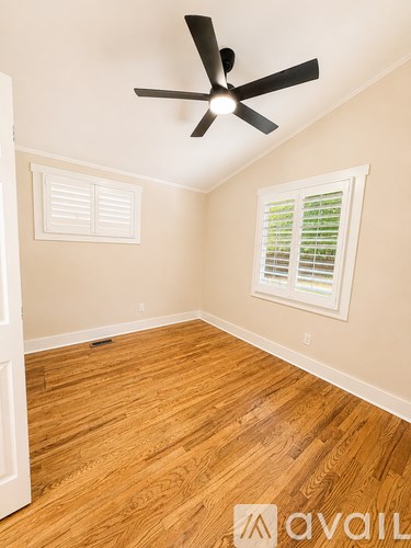 A room with a ceiling fan and a window with blinds.