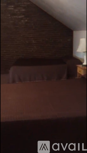 A room with a brown couch and a lamp on a side table.
