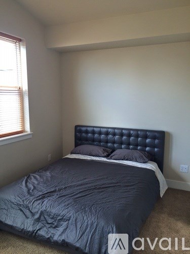 A bedroom with a dark blue bedspread and a tufted headboard.