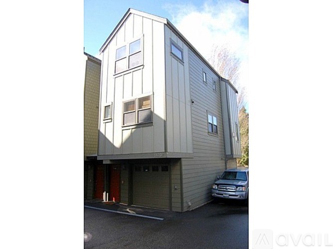 A modern two-story building with a garage door and a car parked in front.