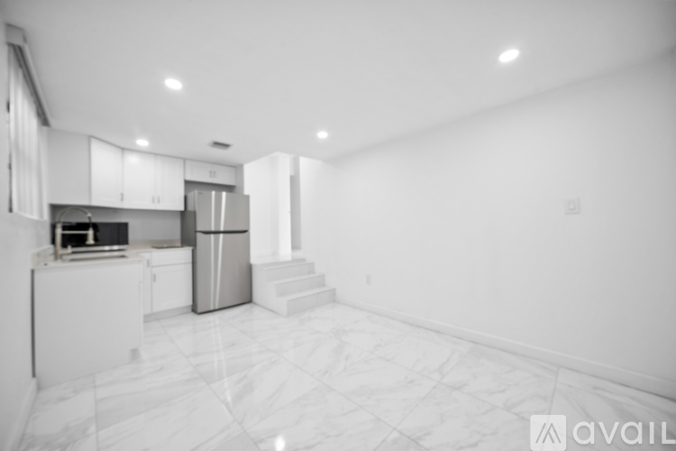 A kitchen with white cabinets and a marble floor.