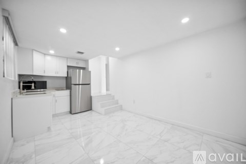 A kitchen with white cabinets and a marble floor.