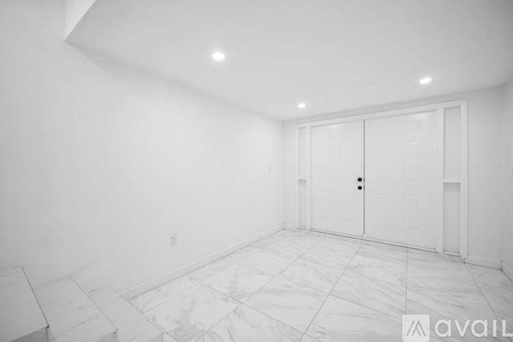 A room with a marble floor and white walls with a door and a window.
