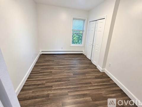 A room with wooden flooring and white walls.