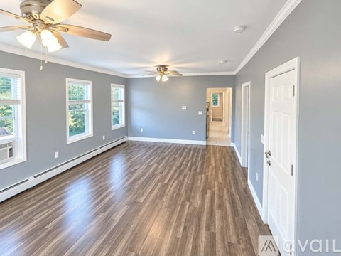 A spacious room with a ceiling fan and hardwood flooring.