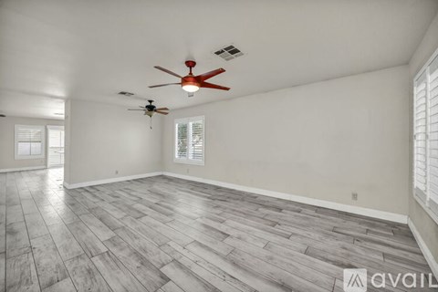 A spacious room with a ceiling fan and hardwood flooring.