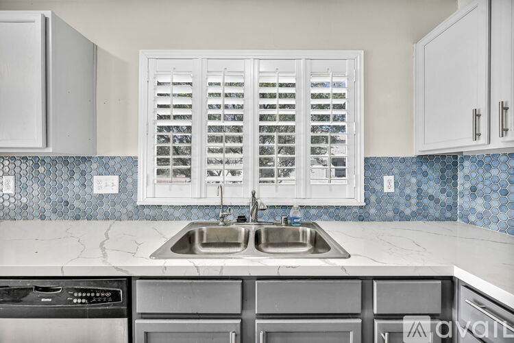 A kitchen with a sink and a window with shutters.