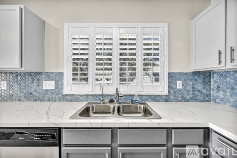 A kitchen with a sink and a window with shutters.