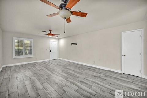 A room with a ceiling fan and a window with blinds.