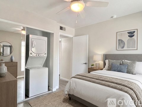 A bedroom with a bed, a dresser, and a wall-mounted fan.