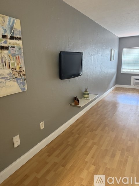 A room with a grey wall and a flat screen TV mounted on it.