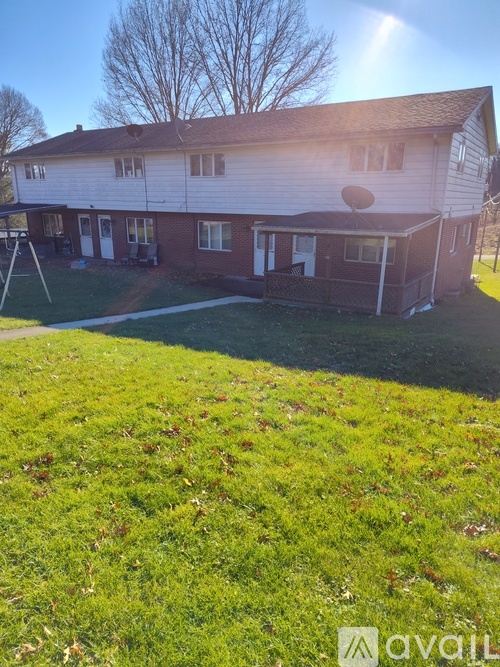 A house with a white and brown exterior is surrounded by a green lawn.