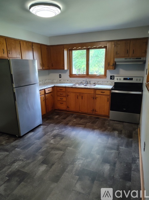 A kitchen with wooden cabinets and a stainless steel refrigerator.