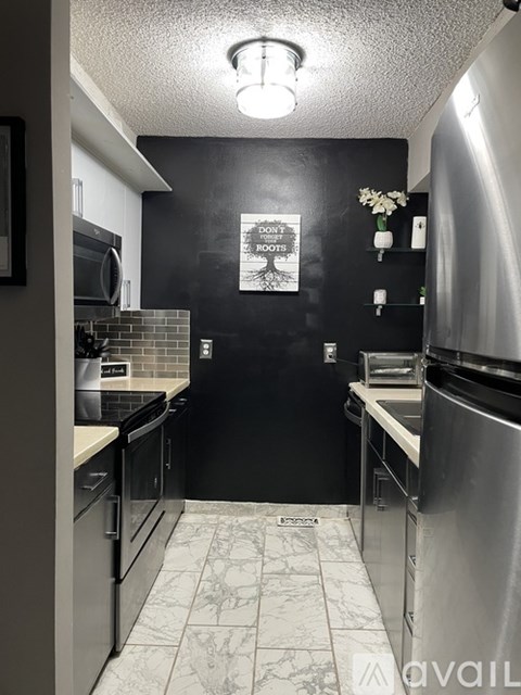 A kitchen with black walls and a white fridge.