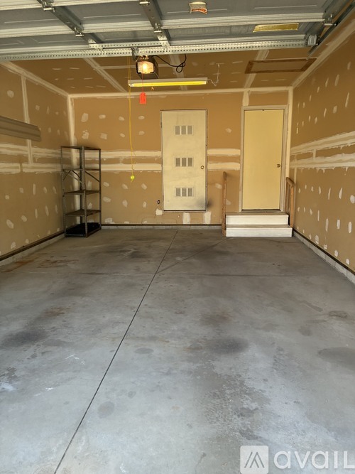 A large empty room with a door in the middle and a light hanging from the ceiling.