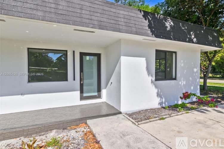 A modern house with a grey roof and white walls is for sale.