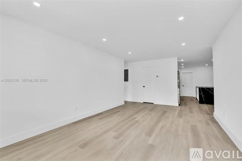 A spacious room with wooden flooring and white walls.