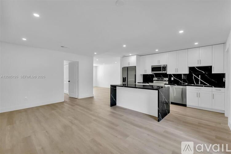 A modern kitchen with white cabinets and a black island.