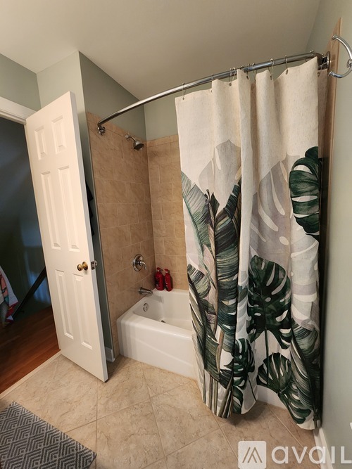 A bathroom with a shower curtain featuring a leaf pattern.