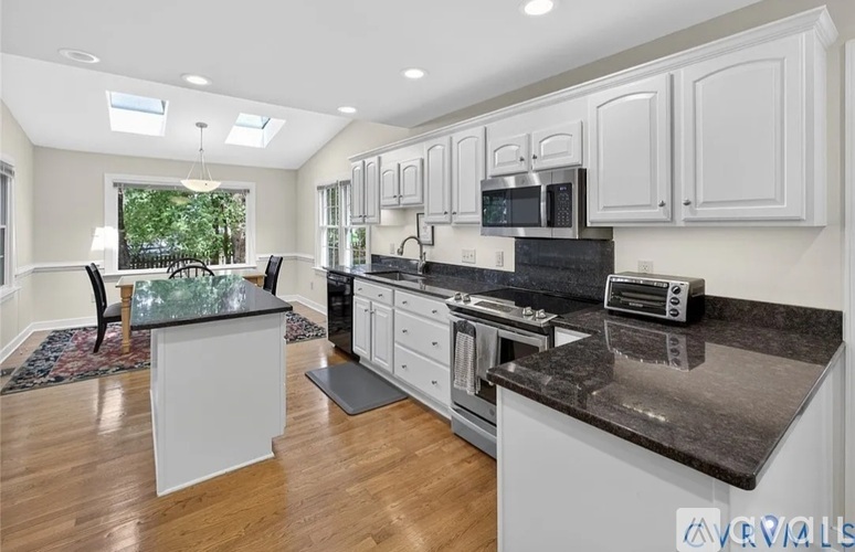A kitchen with white cabinets and black countertops.