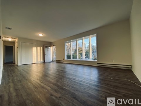 A spacious room with wooden flooring and large windows.