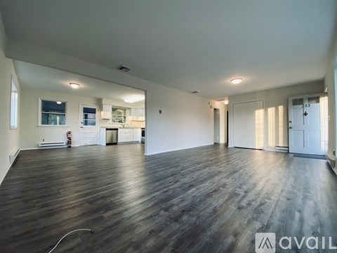 A spacious room with wooden flooring and white walls.