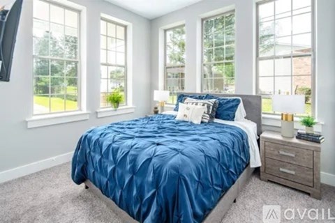 A bedroom with a blue bedspread and a television on the wall.