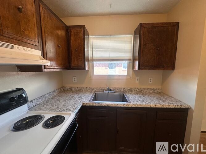 A kitchen with a white stove top oven and a granite counter top.