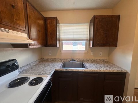 A kitchen with a white stove top oven and a granite counter top.