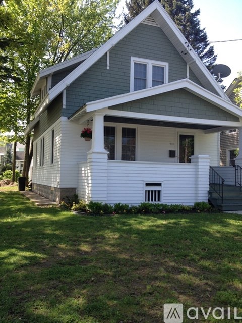 A house with a grey roof and white siding is for sale.