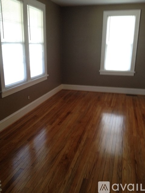 A room with wooden floors and two windows.