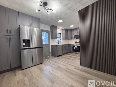 A modern kitchen with wooden floors and stainless steel appliances.