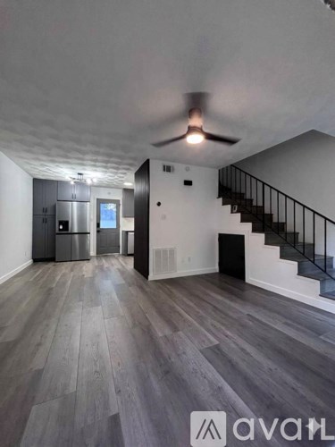 A spacious room with a staircase and a ceiling fan.