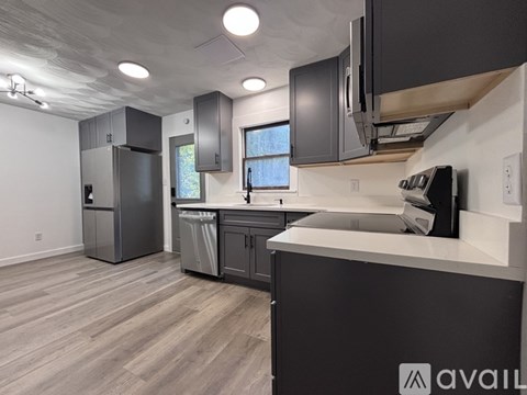 A kitchen with a black fridge, black cabinets, and a black counter.