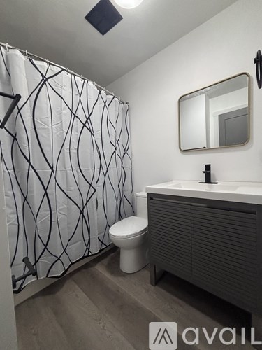 A bathroom with a toilet, sink, and shower curtain.