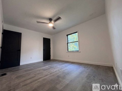 A room with a ceiling fan and a window with a view of trees.