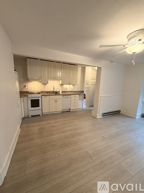 A kitchen with white cabinets and a wooden floor.