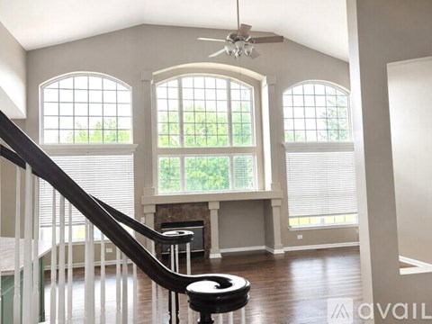 A living room with a staircase and a ceiling fan.