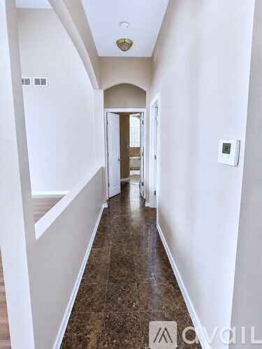 A hallway with a brown floor and white walls.