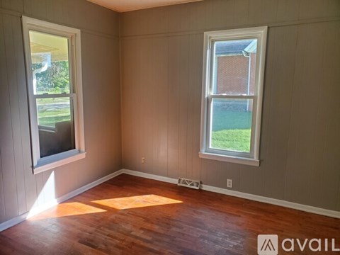 A room with wooden floors and two windows.