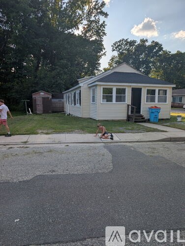 A man is sitting on a bench outside a small house.